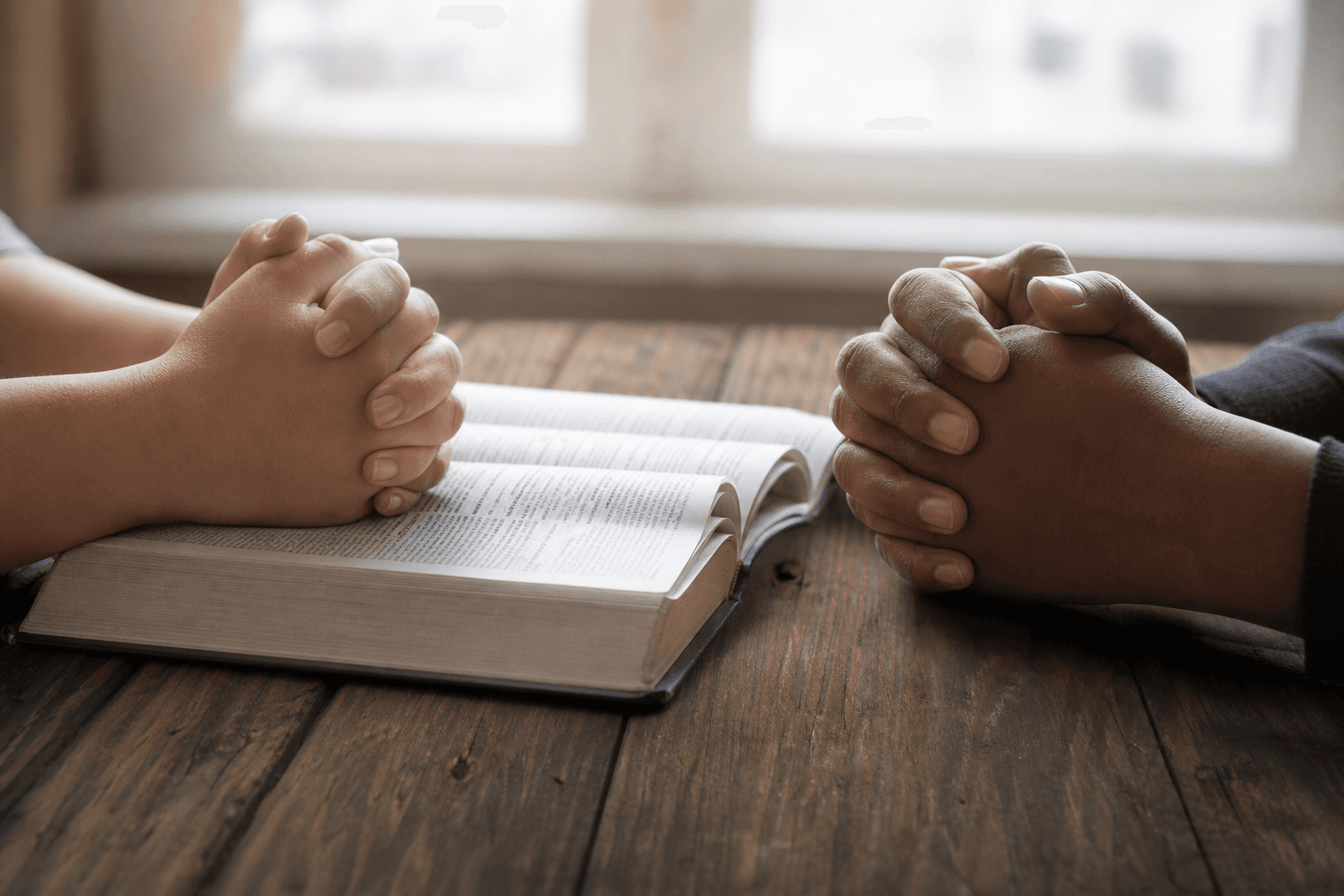 Hands clasped in prayer over an open Bible, representing trust and spiritual agency